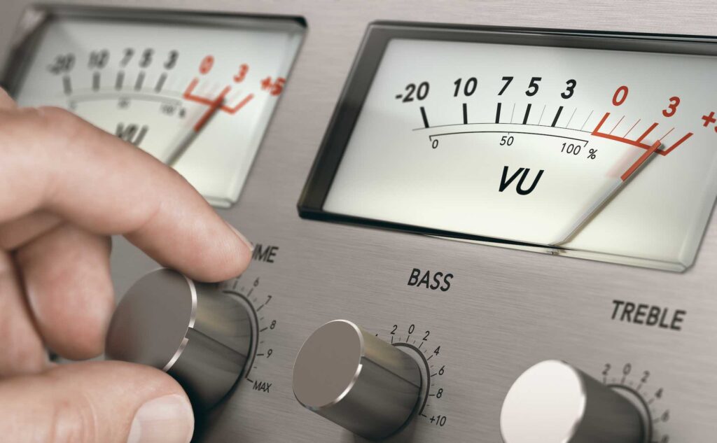 A person's hand turning the volume knob of a vintage analogue amplifier to increase sound volume. 